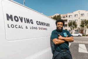 A man in black pants and shirt standing next to a white van