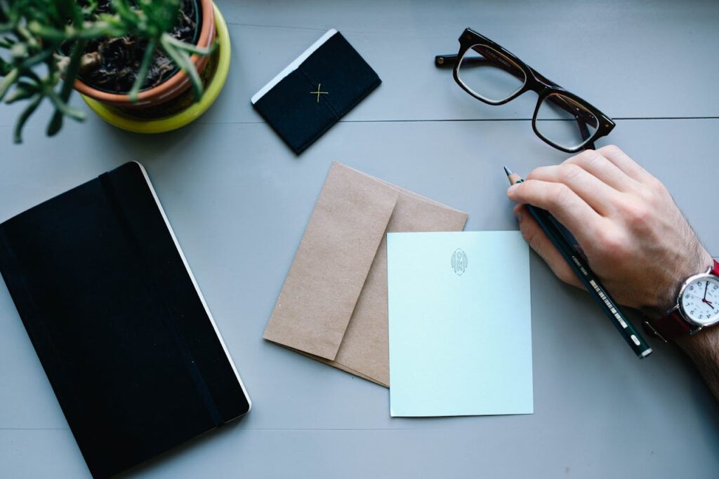 A tablet, glasses, and paper on a gray surface with a tampa business broker holding a pen